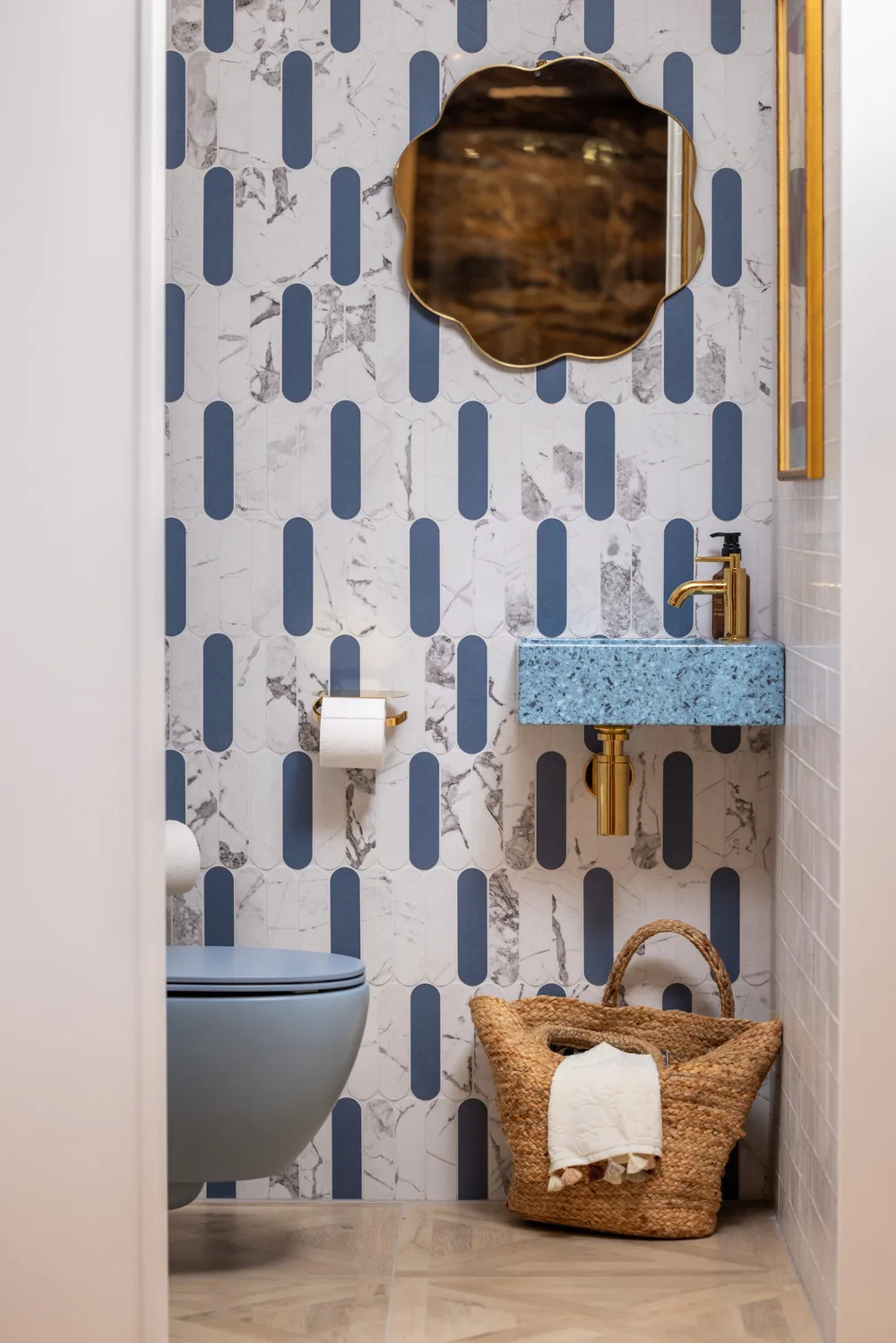 Toiletruimte met blauw-witte tegels en een gouden kraan
