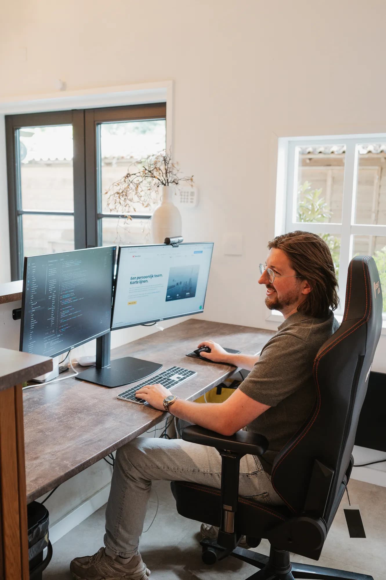 Gerwin Morren aan zijn werkplek met code op twee schermen