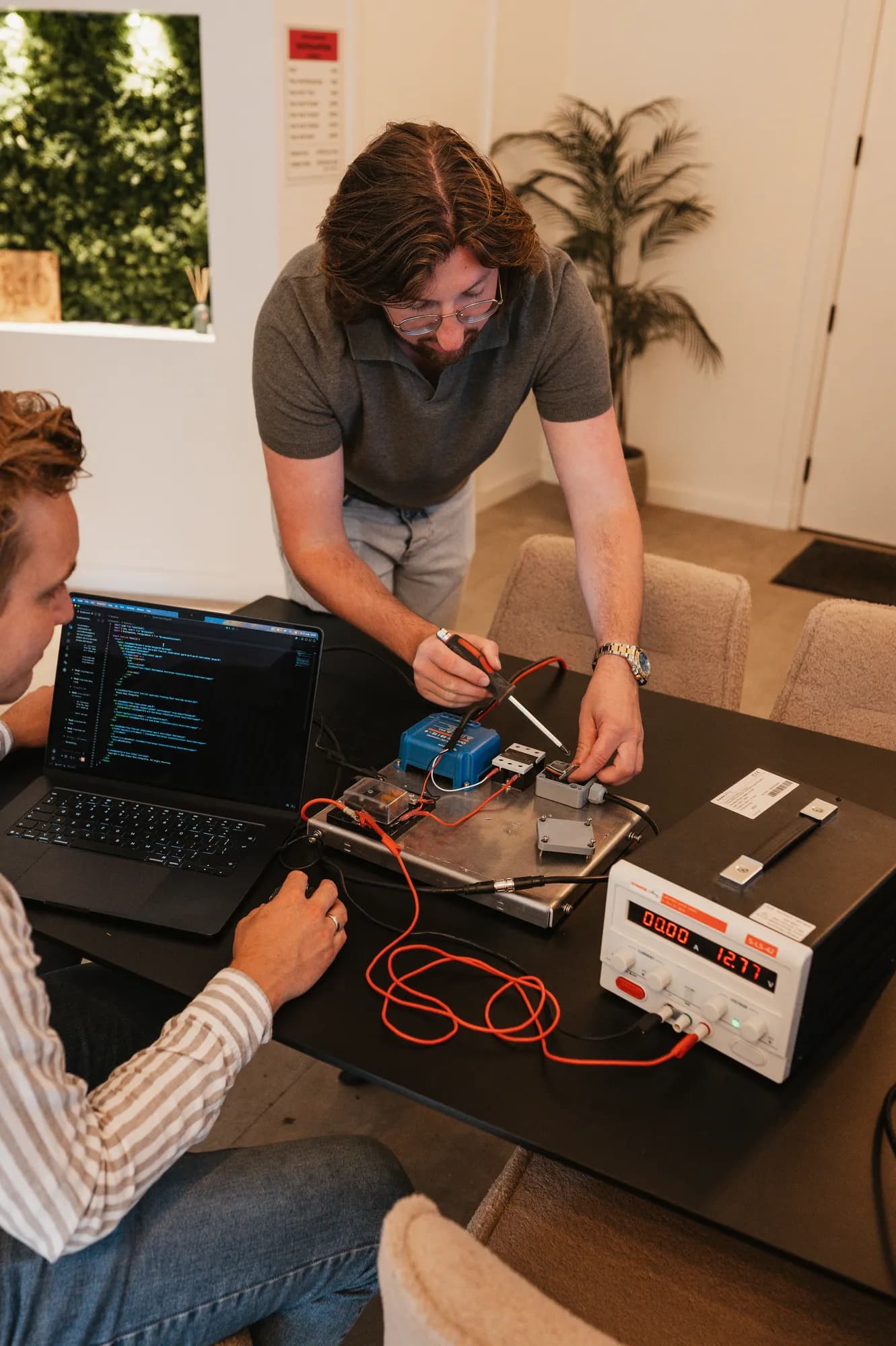 Gerwin Morren soldeert aan een hardwareprototype, Pascal van de Braak achter de laptop met code