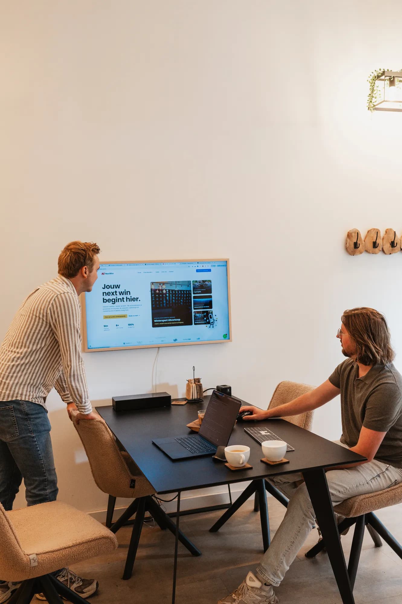 Pascal van de Braak en Gerwin Morren bekijken een website op de laptop, met de Next Win-homepage op het scherm