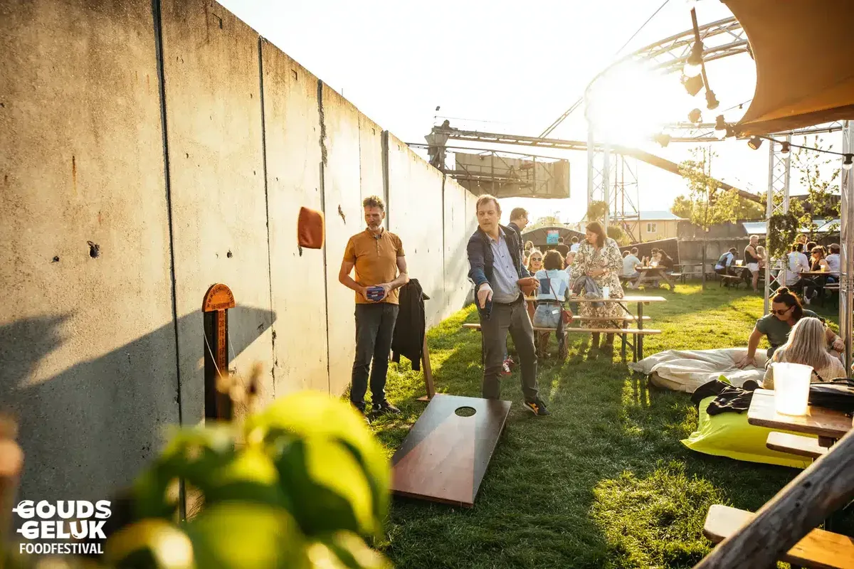 Bezoekers spelen houten Oud-Hollandse spellen op een festivalveld
